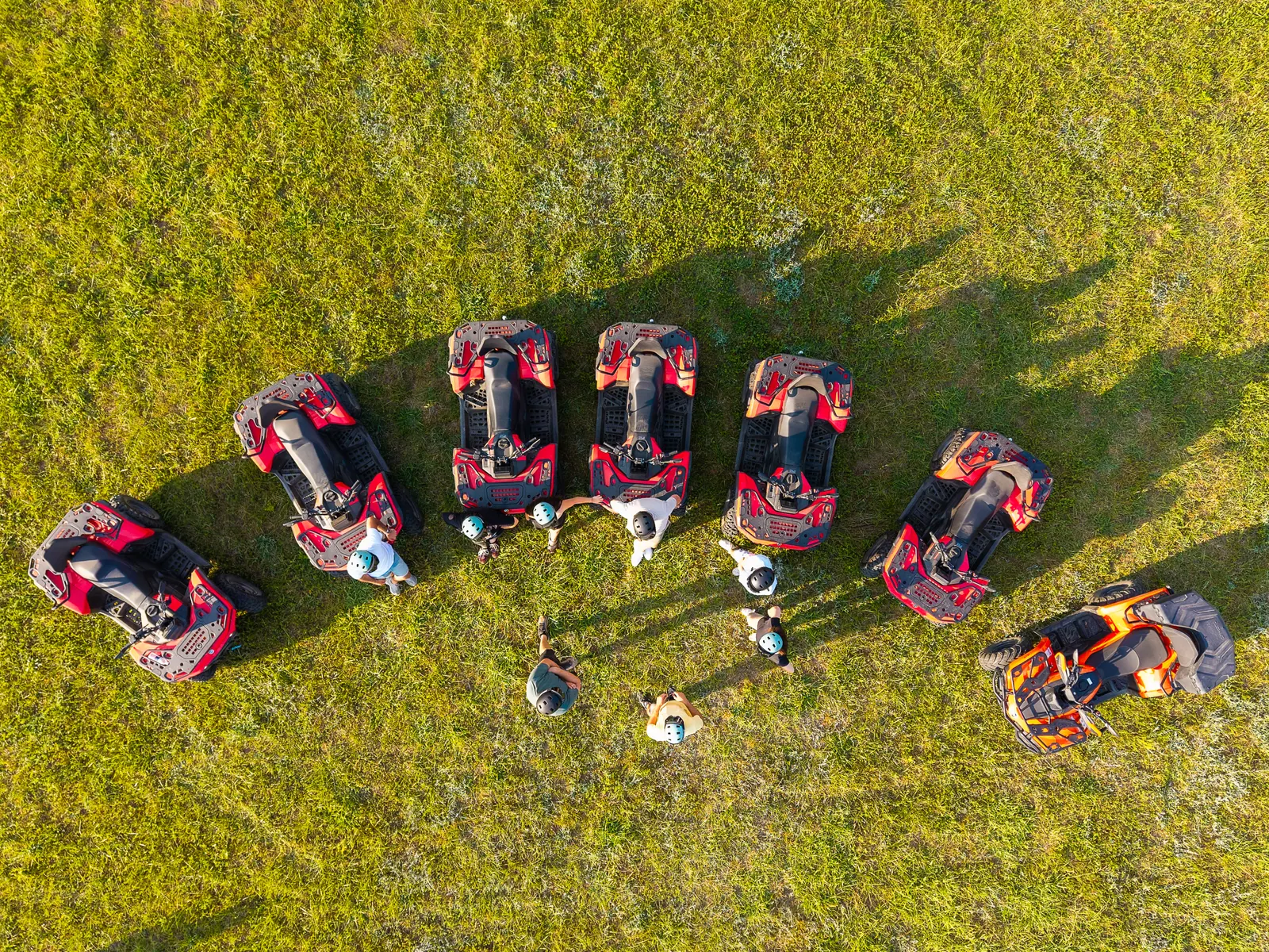 Drone shot of quads parked in formation on a green field