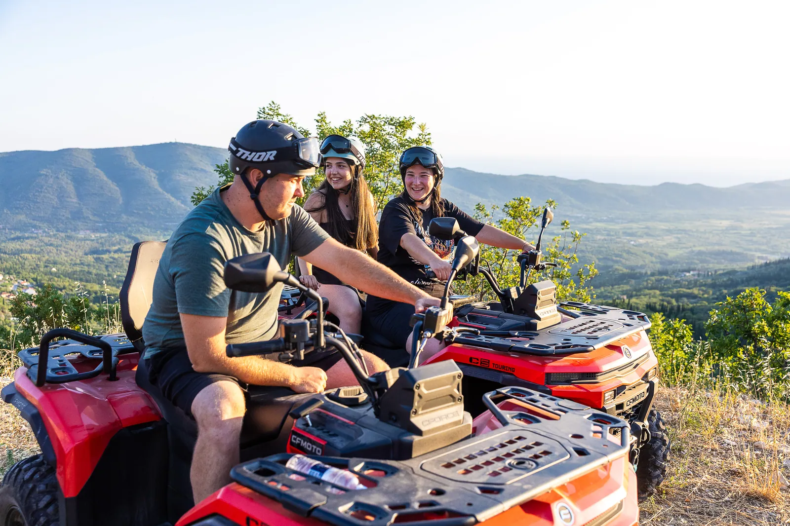 Guide on a quad talking with guests in golden evening light