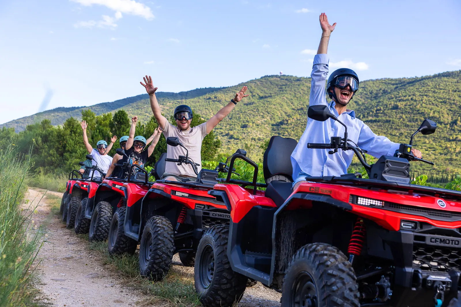 Riders raising their arms on ATV quads in the Konavle field