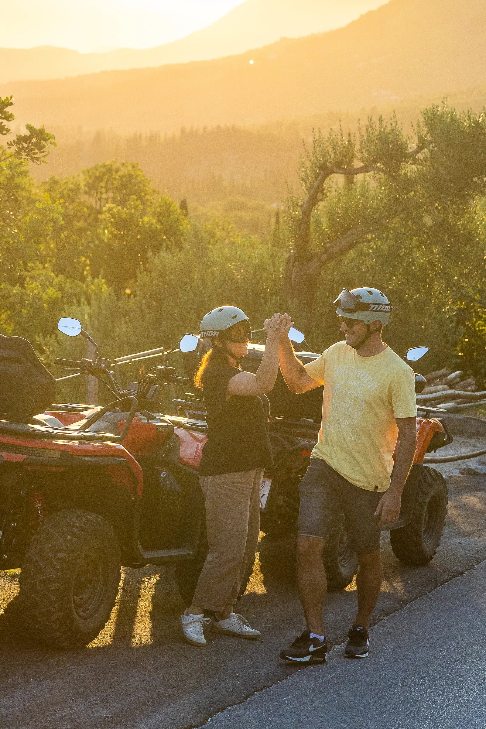 Two riders talking beside their quads at sunset